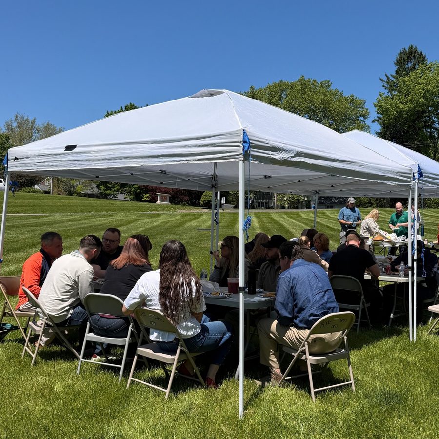 RJB employees seated at tables under white tents at an outdoor company event