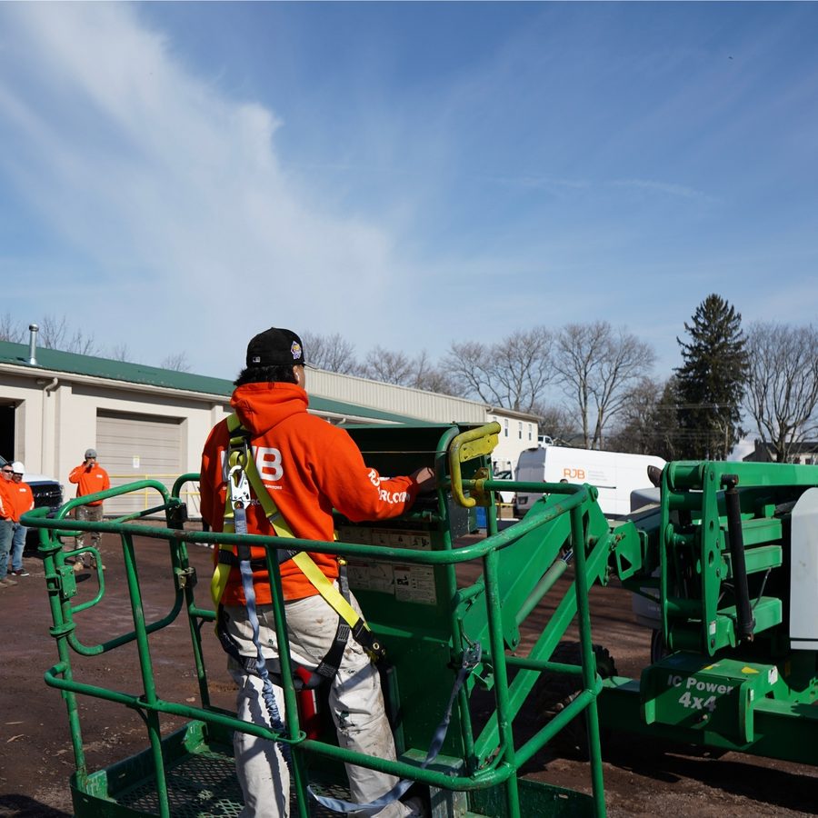RJB team member in a safety harness working from an aerial lift during a hands-on training event